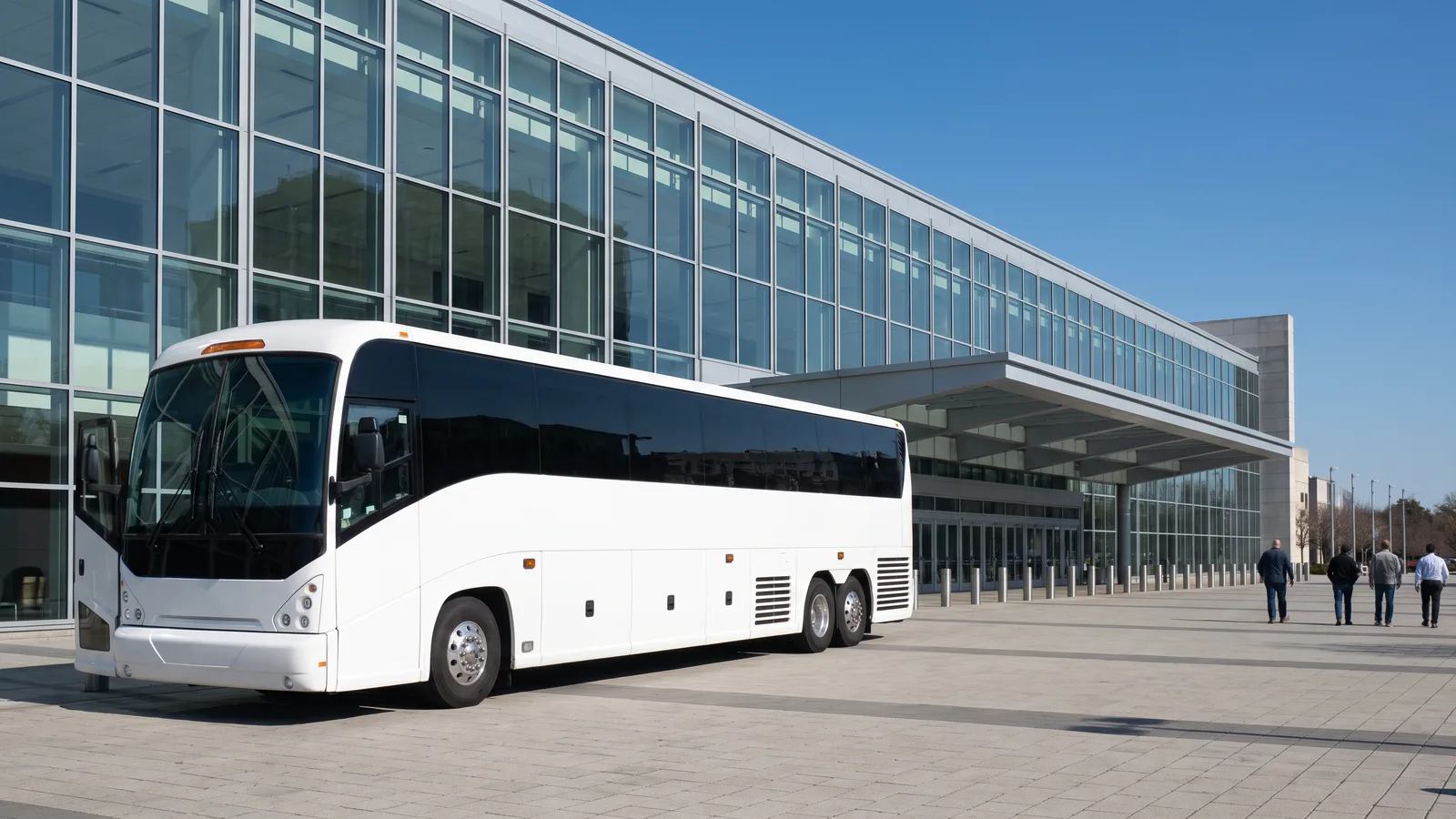 A white coach bus parked at the entrance plaza of a modern glass convention center